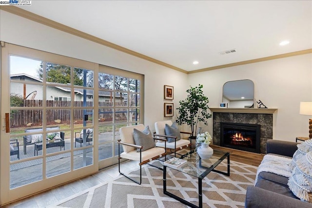 living room featuring ornamental molding, a fireplace, and light wood-type flooring