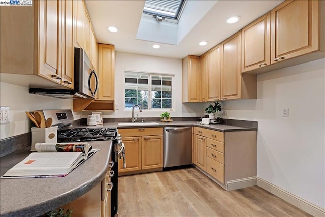 kitchen featuring stainless steel appliances, sink, light wood-type flooring, and a skylight