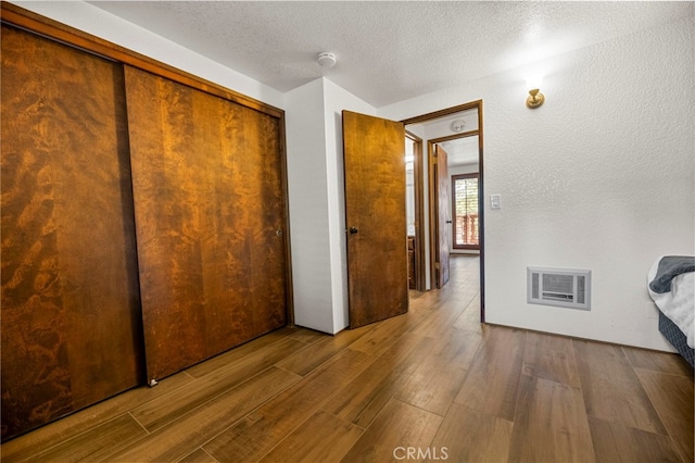 unfurnished bedroom with wood-type flooring, a closet, and a textured ceiling