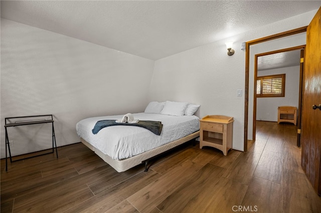 bedroom with a textured ceiling and dark hardwood / wood-style flooring