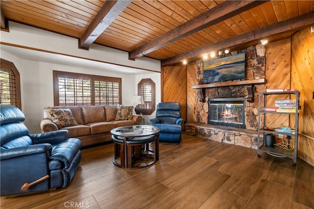 living room featuring beamed ceiling, a stone fireplace, hardwood / wood-style floors, and wooden ceiling