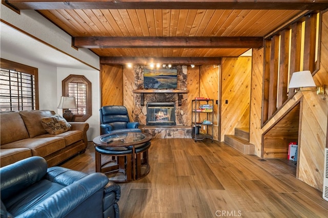 living room with wood ceiling, a stone fireplace, and wood-type flooring