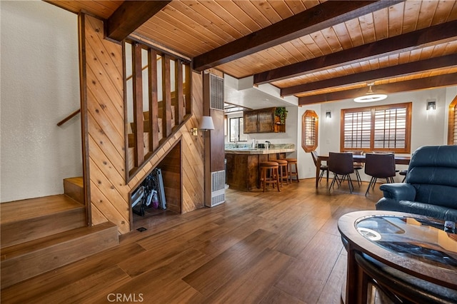 living room featuring beamed ceiling, dark wood-type flooring, and wood ceiling