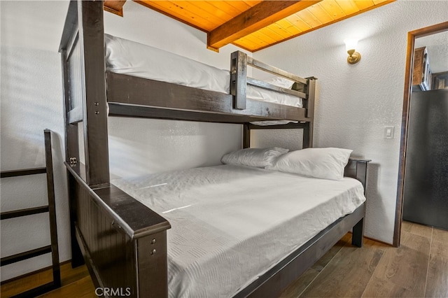 bedroom featuring black refrigerator, wood ceiling, dark hardwood / wood-style floors, and beamed ceiling