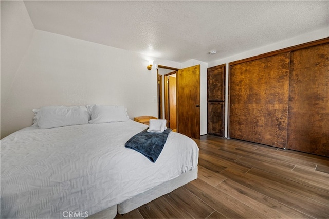 bedroom featuring multiple closets, dark wood-type flooring, and a textured ceiling