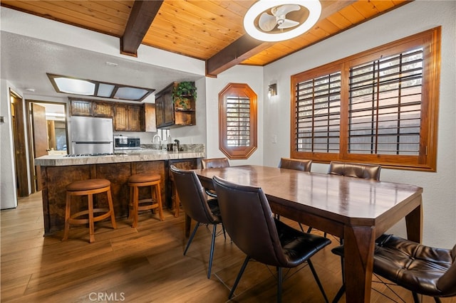 dining area featuring beamed ceiling, hardwood / wood-style floors, and wooden ceiling