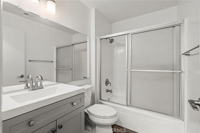 full bathroom featuring vanity, bath / shower combo with glass door, and toilet