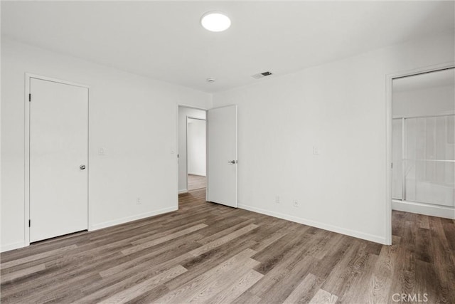 unfurnished bedroom featuring a spacious closet, hardwood / wood-style floors, and a closet