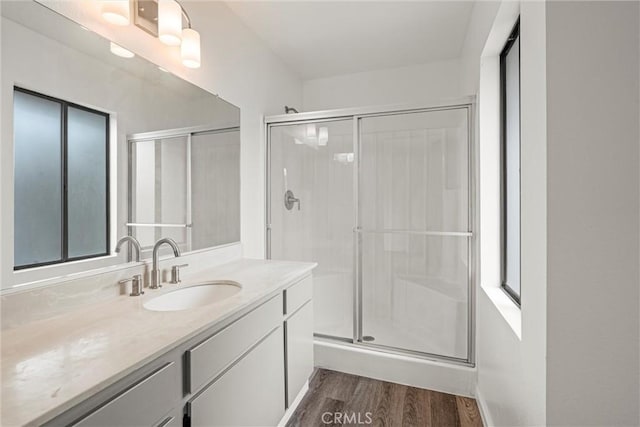 bathroom with hardwood / wood-style flooring, vanity, and a shower with shower door