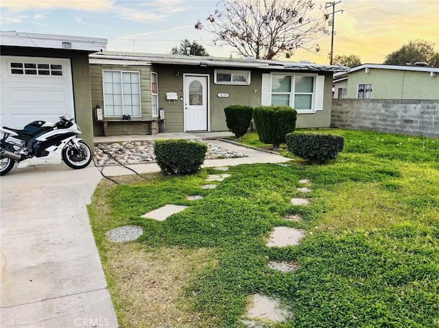 ranch-style home featuring a garage and a lawn