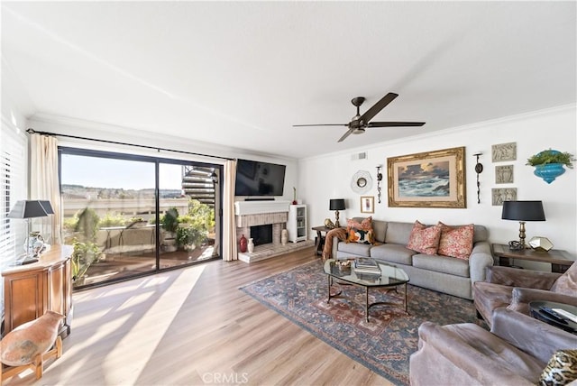 living room featuring crown molding, light hardwood / wood-style flooring, and ceiling fan