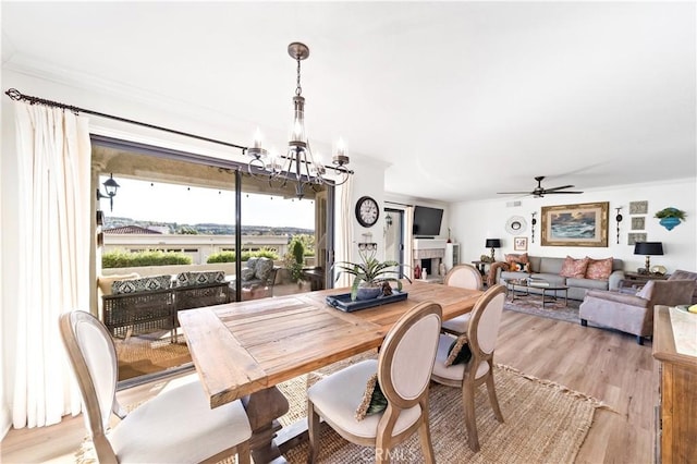 dining space featuring crown molding, ceiling fan with notable chandelier, and light wood-type flooring