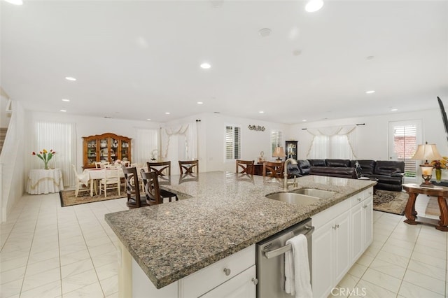 kitchen with sink, white cabinetry, light stone counters, stainless steel dishwasher, and a kitchen island with sink