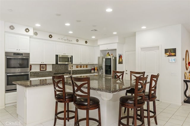 kitchen with a large island, white cabinetry, dark stone countertops, and appliances with stainless steel finishes