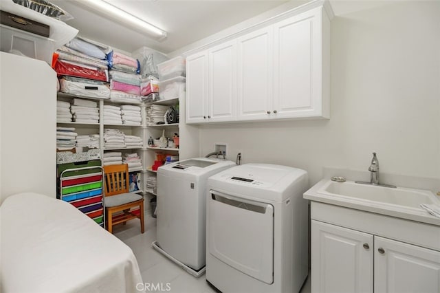 washroom featuring cabinets, washing machine and dryer, and sink