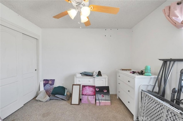 bedroom with a closet, ceiling fan, light carpet, and a textured ceiling