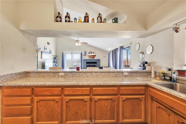 kitchen featuring a brick fireplace, plenty of natural light, ceiling fan, and vaulted ceiling