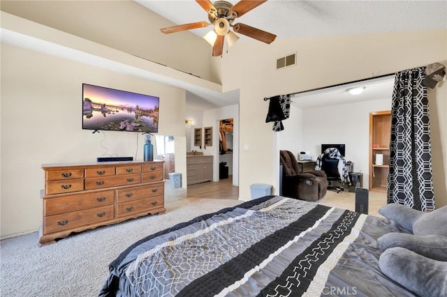 carpeted bedroom featuring ceiling fan, ensuite bathroom, and high vaulted ceiling