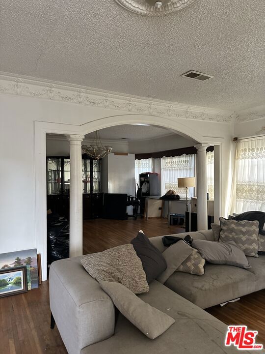 living room with ornate columns, ornamental molding, dark hardwood / wood-style floors, and a textured ceiling