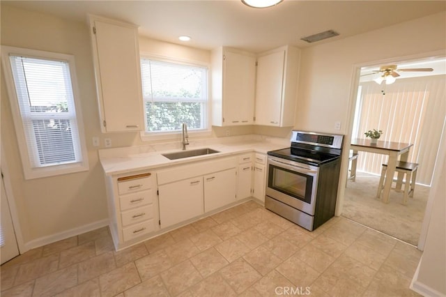 kitchen with stainless steel range with electric stovetop, sink, white cabinetry, and ceiling fan