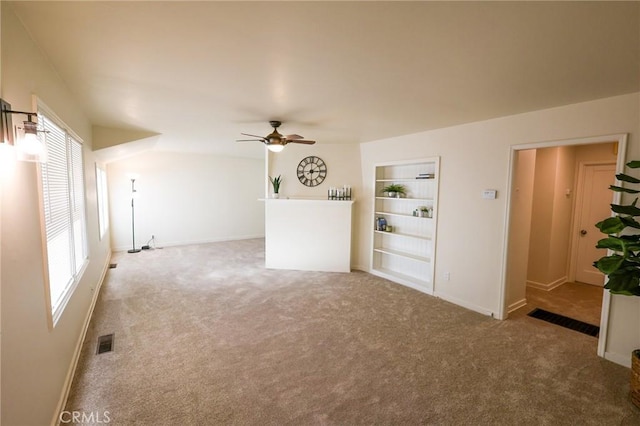 unfurnished living room with carpet floors, built in features, and ceiling fan