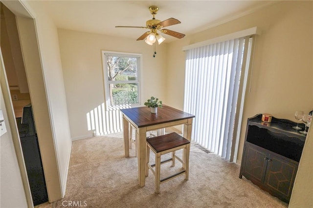 dining space with light colored carpet and ceiling fan