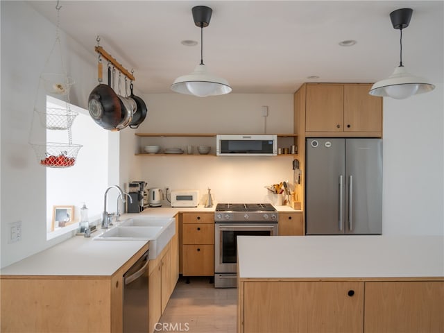 kitchen featuring appliances with stainless steel finishes, sink, pendant lighting, and light brown cabinets