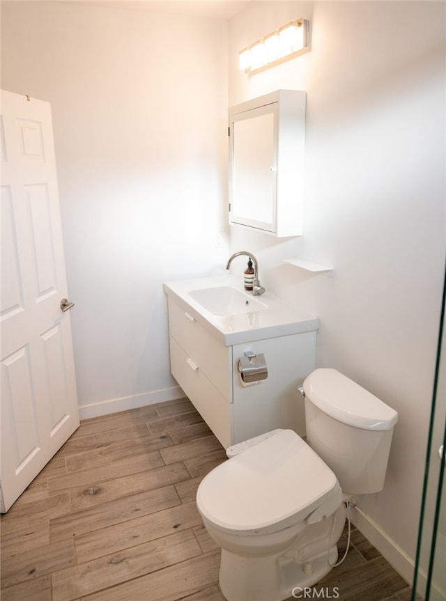 bathroom with hardwood / wood-style flooring, vanity, and toilet