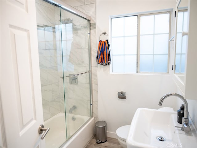 full bathroom featuring toilet, bath / shower combo with glass door, sink, and hardwood / wood-style floors