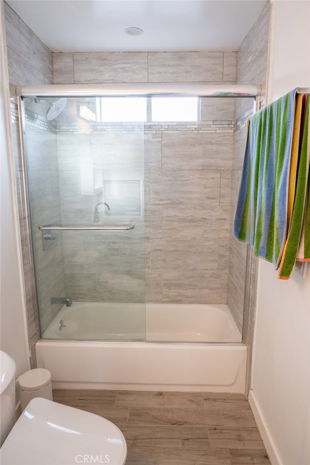 bathroom featuring combined bath / shower with glass door and toilet