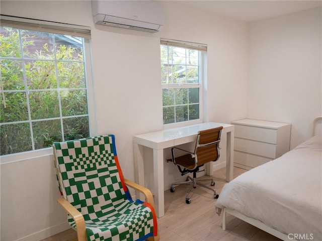 bedroom with a wall mounted air conditioner and light hardwood / wood-style flooring