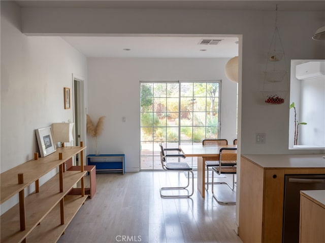 dining space featuring a wall mounted AC and light wood-type flooring