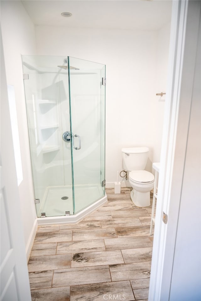 bathroom featuring toilet and a shower with shower door