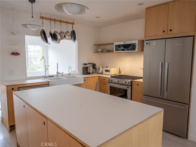 kitchen with appliances with stainless steel finishes, light brown cabinetry, a center island, and sink