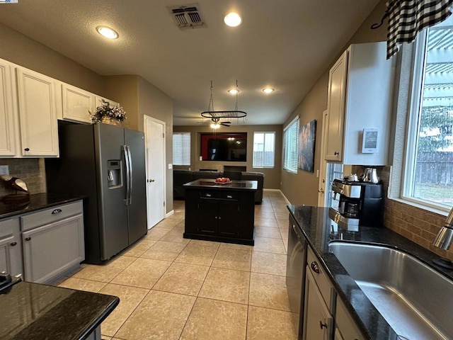 kitchen featuring stainless steel refrigerator with ice dispenser, sink, light tile patterned floors, ceiling fan, and white cabinets