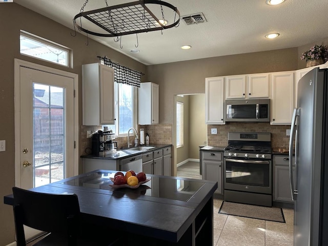 kitchen featuring sink, appliances with stainless steel finishes, white cabinetry, backsplash, and light tile patterned flooring