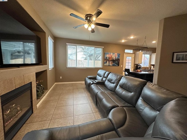 living room with a tiled fireplace, light tile patterned floors, plenty of natural light, and a textured ceiling