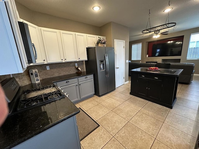 kitchen featuring tasteful backsplash, white cabinetry, light tile patterned floors, stainless steel appliances, and a textured ceiling