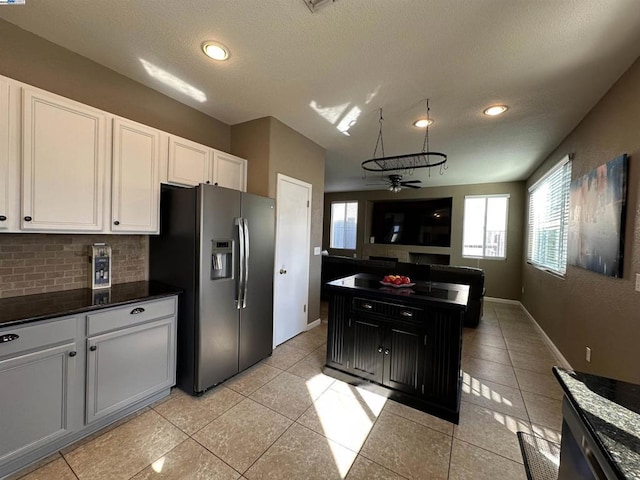 kitchen with light tile patterned flooring, stainless steel fridge with ice dispenser, white cabinets, ceiling fan, and backsplash