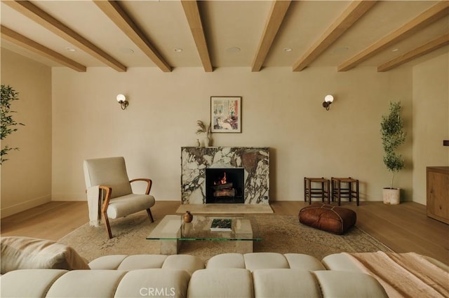 living room featuring a fireplace, beam ceiling, and light wood-type flooring