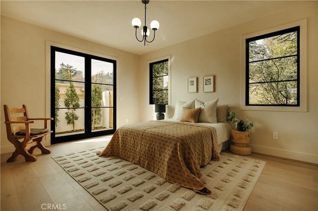 bedroom featuring multiple windows, a notable chandelier, and light wood-type flooring