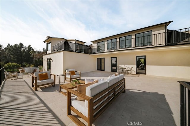 rear view of property featuring an outdoor living space, a patio, and a balcony