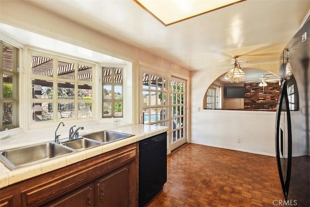 kitchen with decorative light fixtures, black appliances, sink, dark brown cabinets, and dark parquet flooring