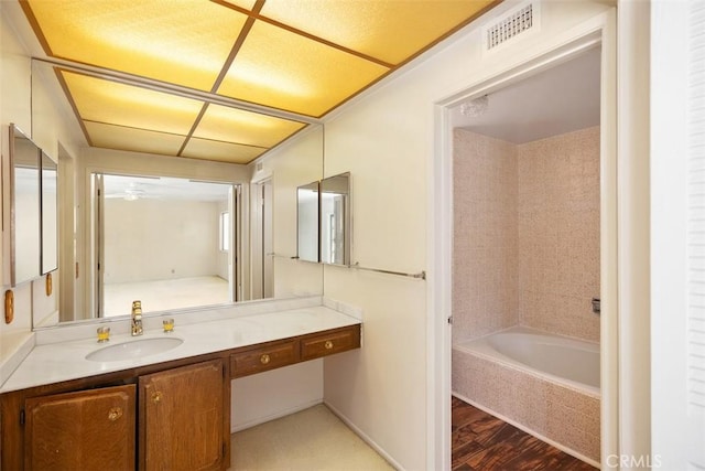 bathroom with vanity, wood-type flooring, and tiled tub