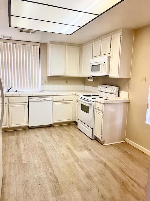 kitchen featuring white cabinetry, white appliances, and light hardwood / wood-style flooring