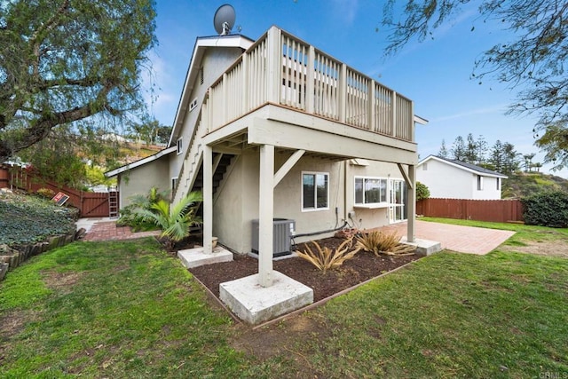 rear view of house with a wooden deck, a yard, central AC unit, and a patio area