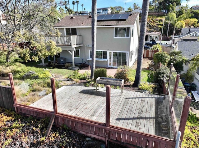 back of house with cooling unit, a balcony, a deck, and solar panels