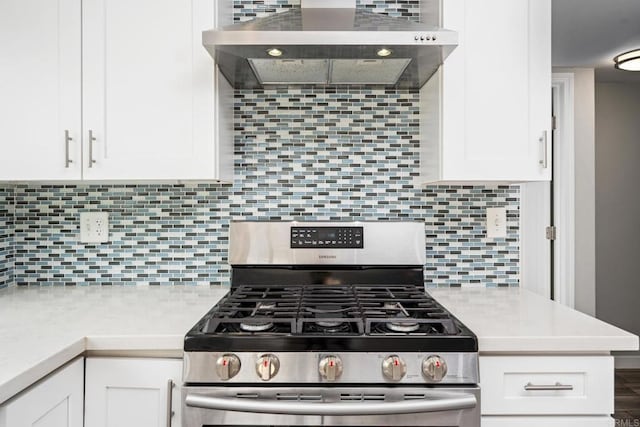 kitchen with tasteful backsplash, wall chimney range hood, gas stove, and white cabinets