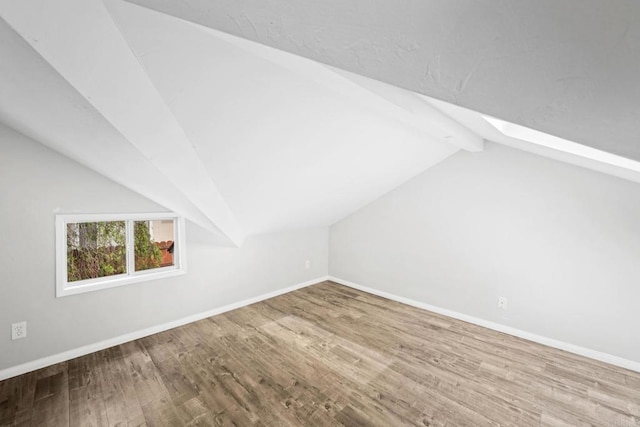 additional living space with hardwood / wood-style flooring and lofted ceiling with skylight