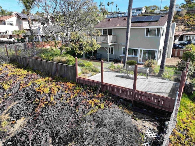 rear view of house featuring a balcony, a deck, and solar panels